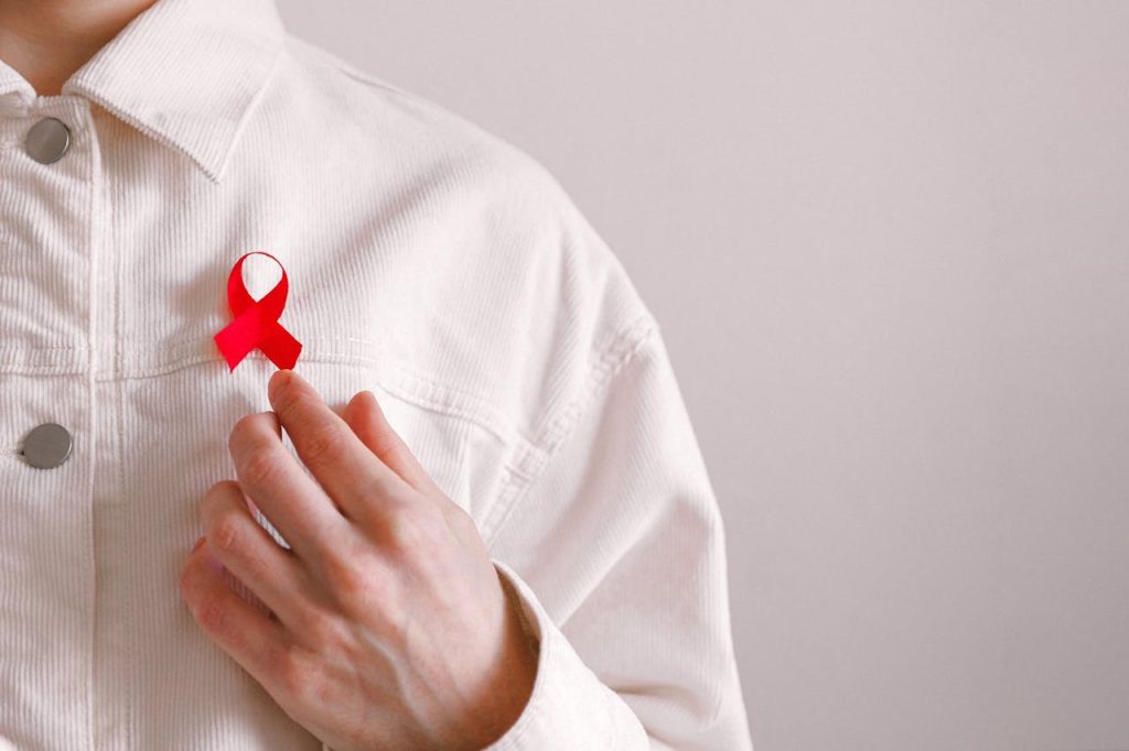 Close-up of a red ribbon on a white shirt symbolizing AIDS awareness and support.